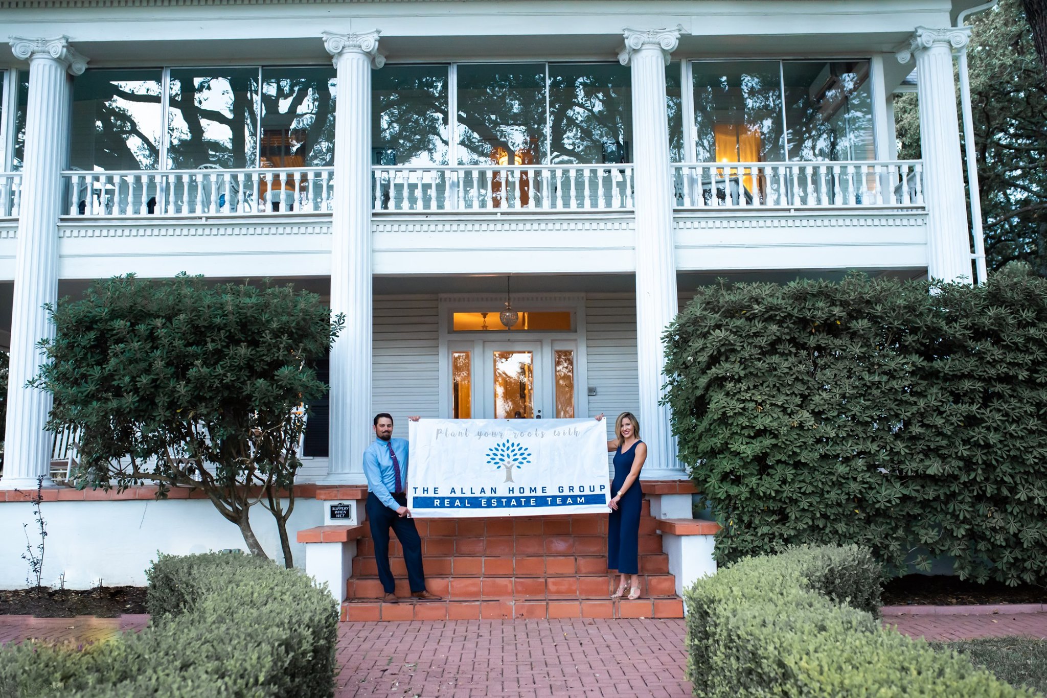 Dustin and Kristin Allan holding The Allan Home Group banner